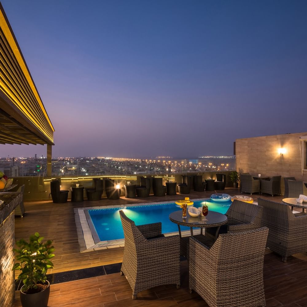 Rooftop lounge with pool and night view at Naviti By Warwick Dammam.