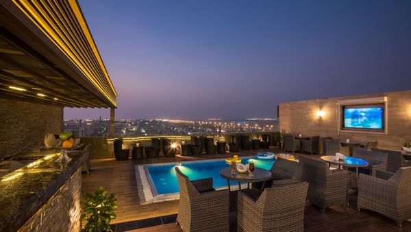 Rooftop lounge with pool and night view at Naviti By Warwick Dammam.