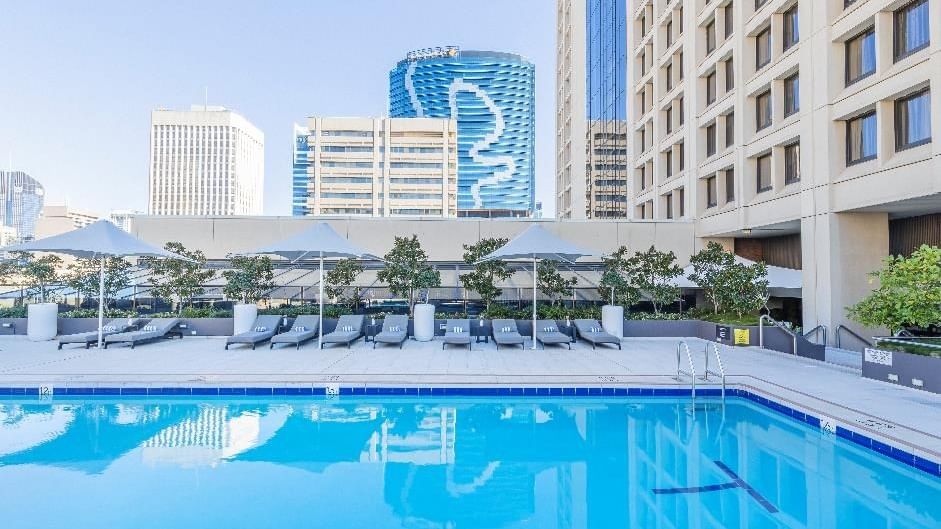 Poolside dining area with loungers and city view at Sofitel Brisbane Central