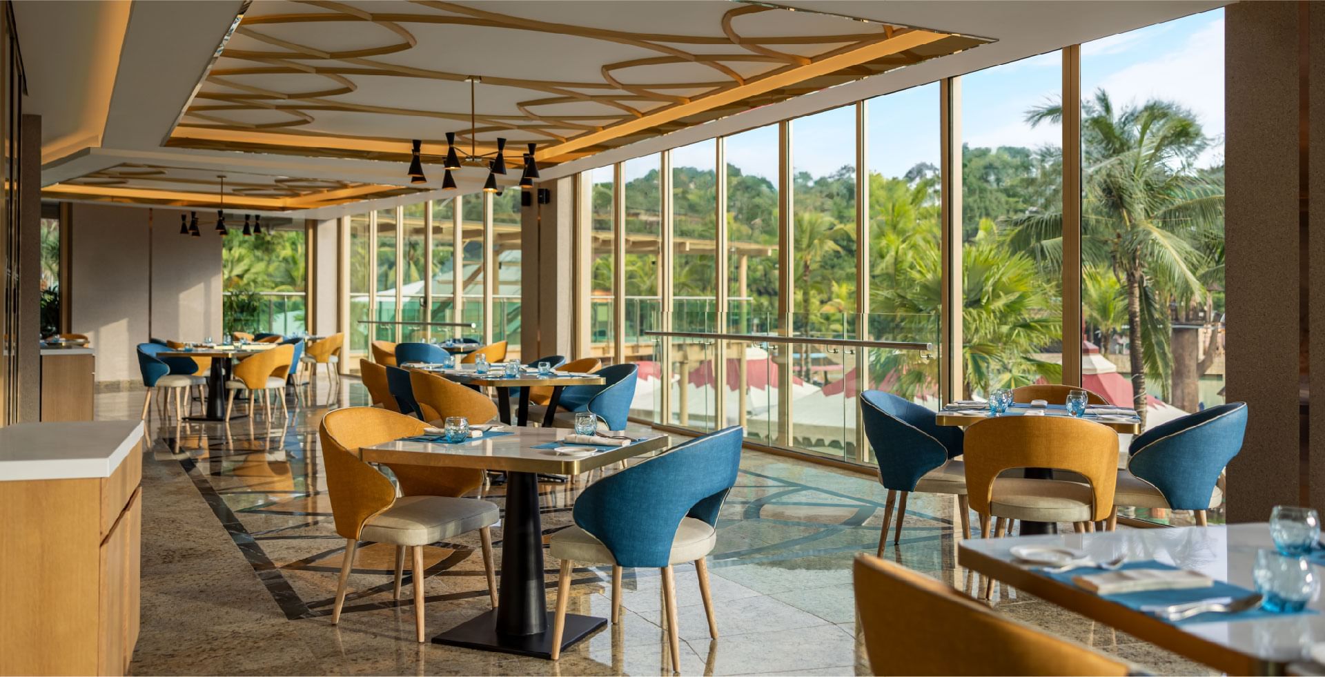 Bright and modern restaurant at Sunway Resort, offering panoramic views of lush greenery through large windows