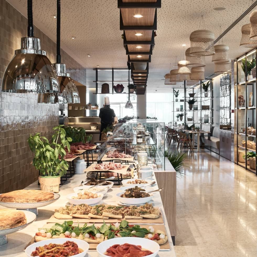 Buffet setup in a modern dining area with various dishes at Falkensteiner Hotel & Spa Jesolo