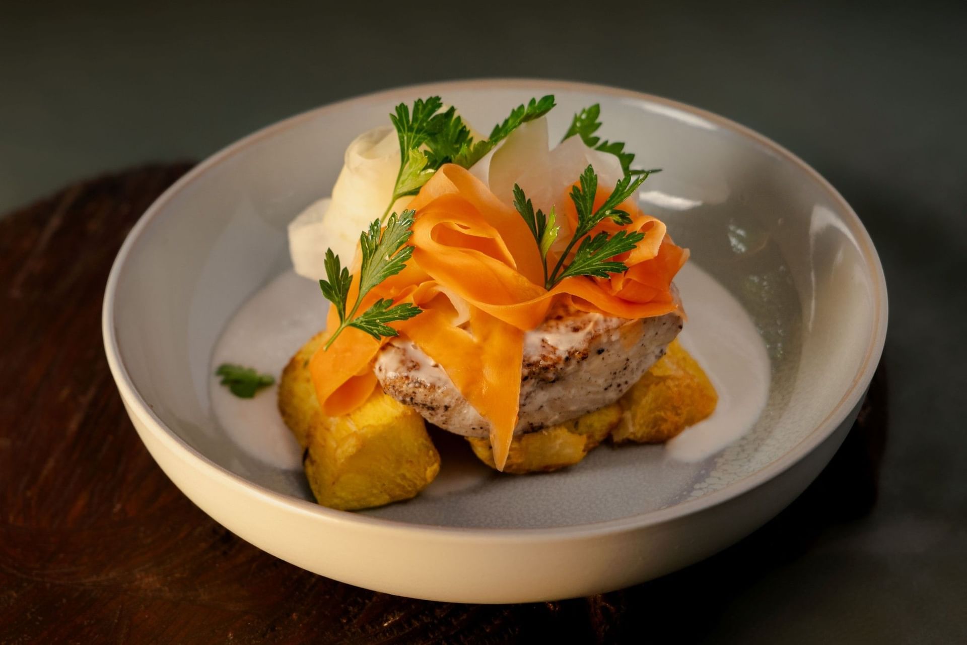 Gourmet fish dish served with carrot ribbons and potatoes in a creamy white sauce at Cala Luna Boutique Hotel