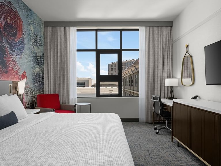 Capitol Double Queen with a large bed, a red chair, and a desk with a city view at Hotel 43 Boise