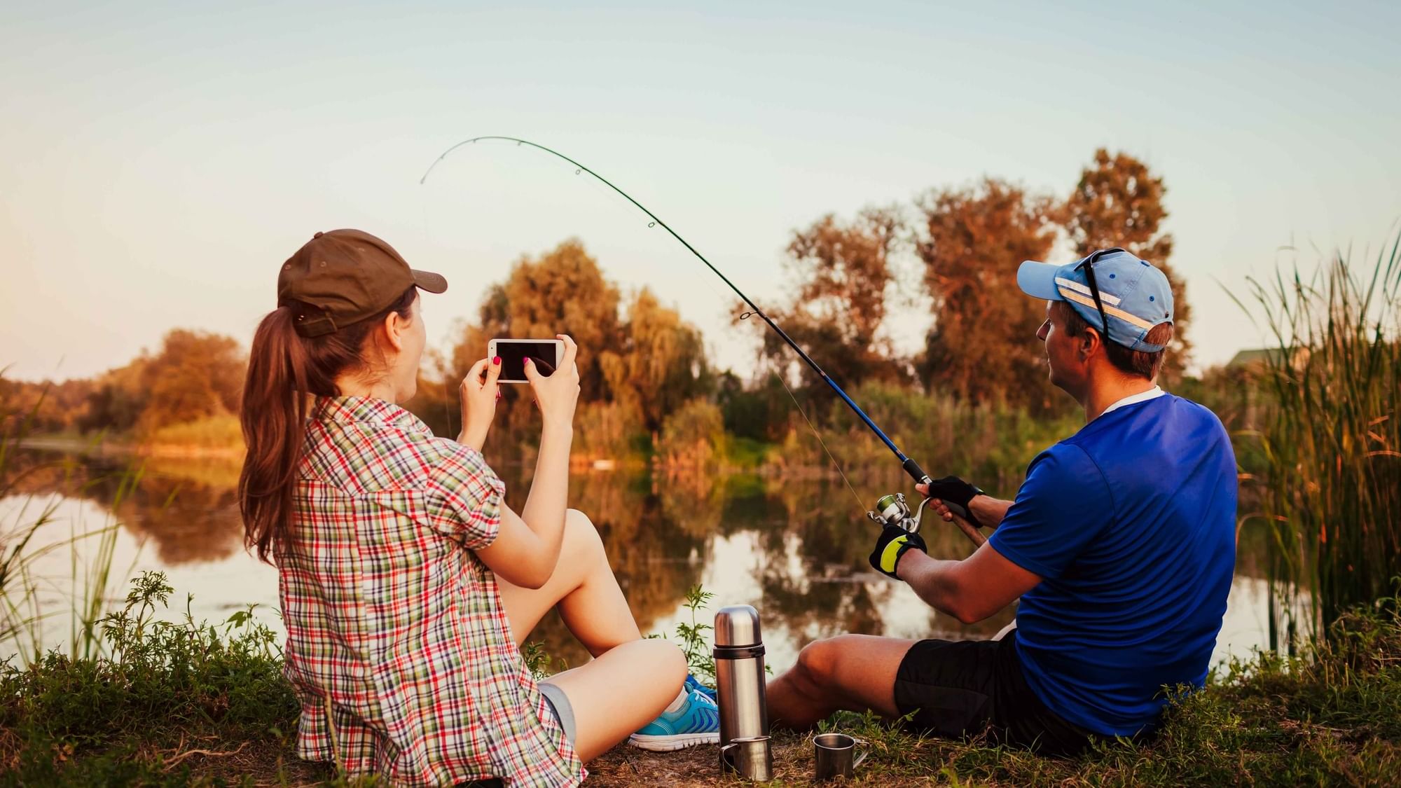 Couple fishing by a lake at sunset near Cove Pocono Resorts