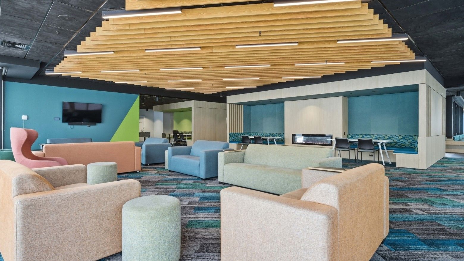 Modern lounge area with colorful sofas, a TV, and a wooden ceiling at Mayoral Drive Student Accommodation.