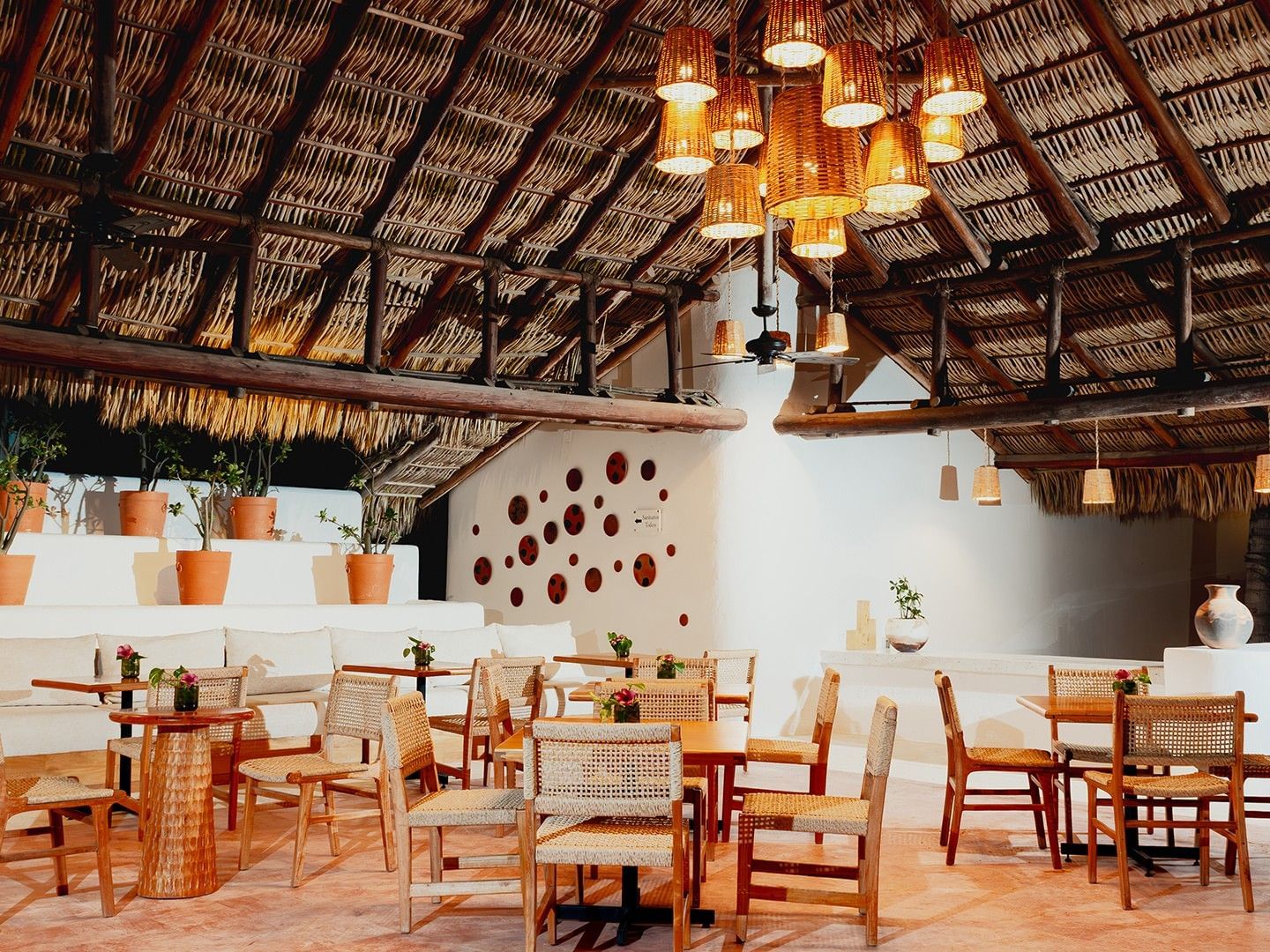 Dining area with woven chairs, a cushioned seating area, & thatched roof in Camino Real Club at Camino Real Zaashila Huatulco
