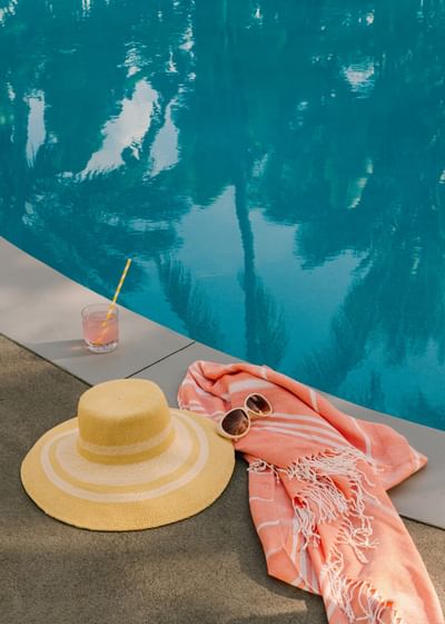 Sun hat, sunglasses, towel, and a cocktail by the beautiful outdoor blue pool at the Kenmore Village Hotel South Beach