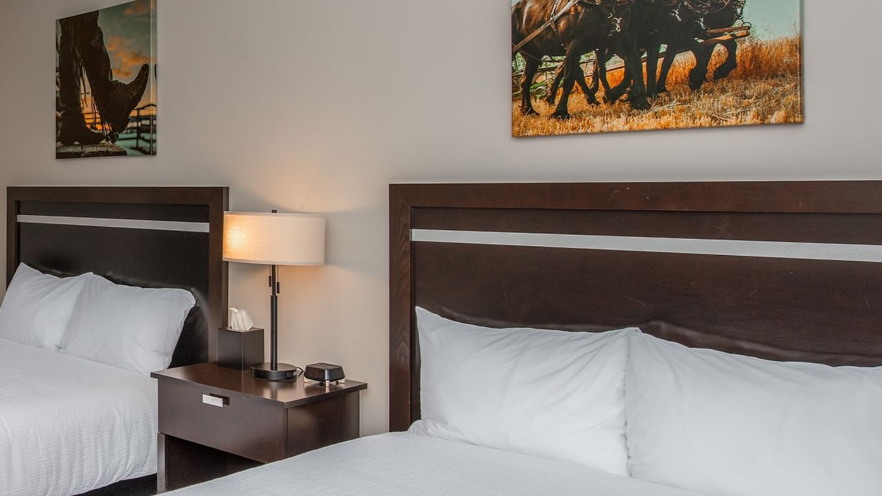Two queen beds at Coast Innisfail Hotel with bedside table and artwork