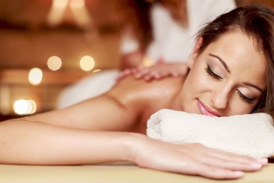 Relaxed guest enjoying a back massage by a therapist under soft ambient lighting at Oregon Garden Resort