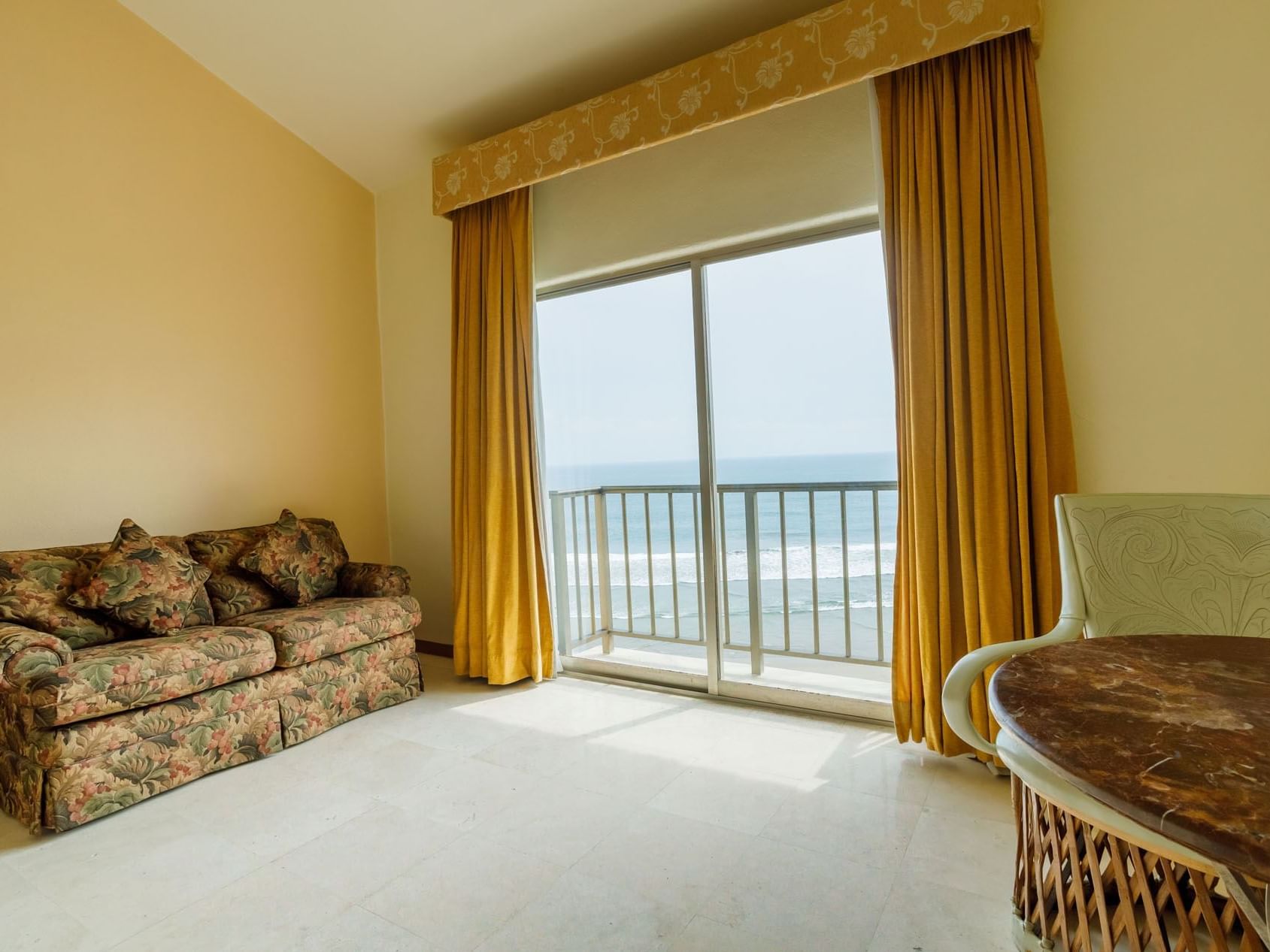 Scenic ocean view from King Grand Class featuring a floral sofa and golden curtains at Quinta Real Acapulco