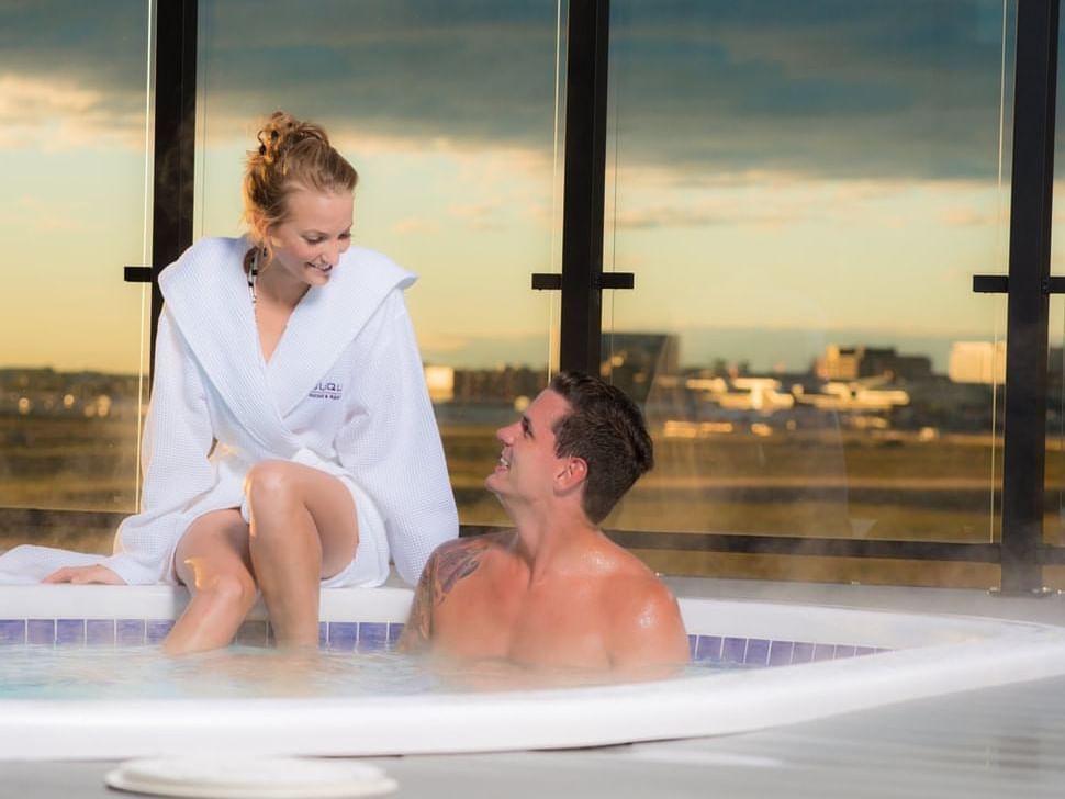 Couple looking at each other in a hot bathtub at Applause Hotel Calgary