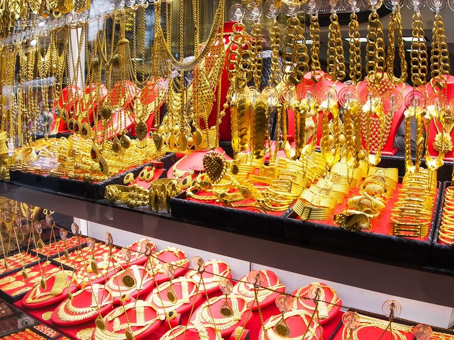Display of shiny gold jewellery and ornaments on red velvet at Gold Souk Dubai near DAMAC Hotels & Resorts