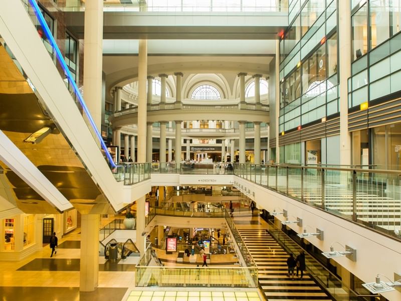 Modern glass and steel shopping mall interior with shoppers walking at Pickwick San Francisco.
