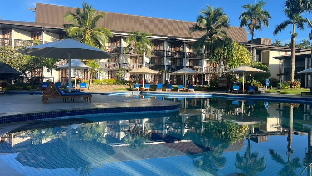 Large swimming pool with umbrellas and lounge chairs at Warwick Fiji Resort and Spa in Korolevu.