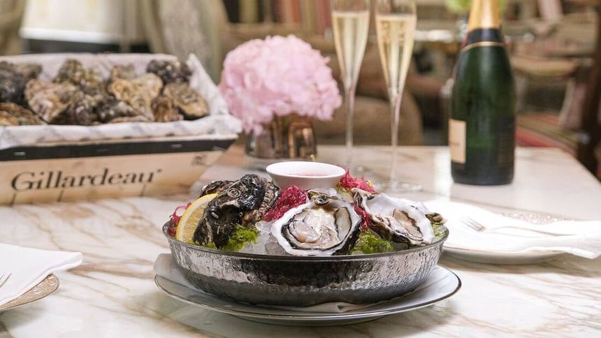 Table setting with a plate of fresh oysters, a basket of oysters, & champagne flutes in Park Lounge at Park Hyatt Saigon