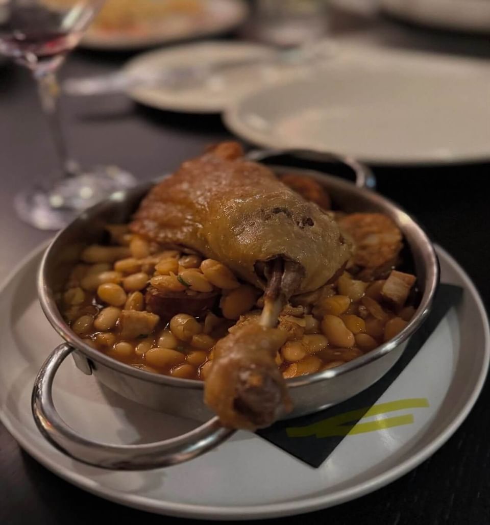 A duck leg on top of a bed of corn