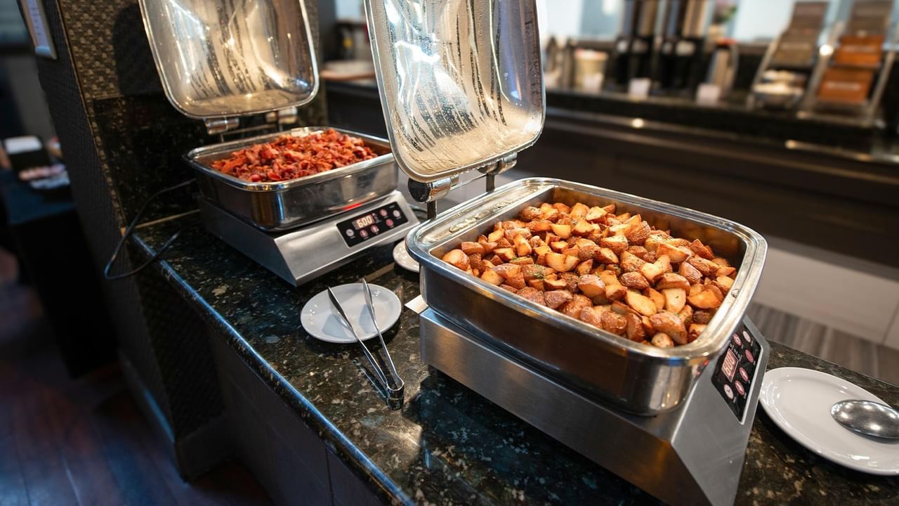 Breakfast buffet with hot dishes including sausages and beans in chafing dishes at Coast Calgary University Area Hotel by APA