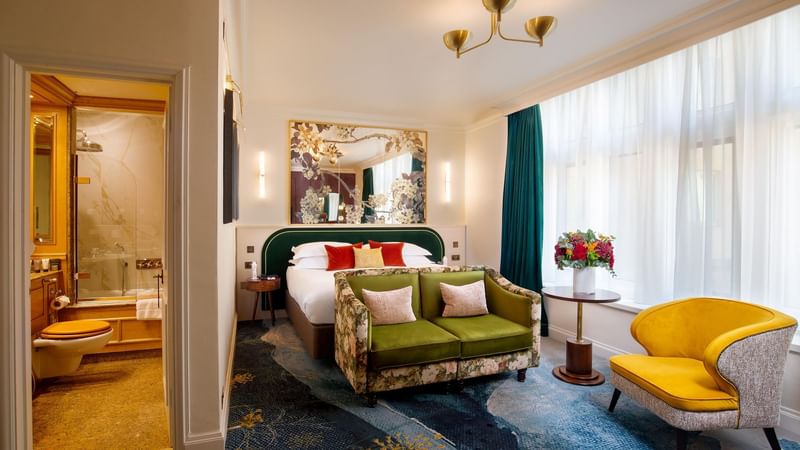 Luxurious room with bed, seating area, chandelier, and large windows with white curtains at Warwick Hotels and Resorts