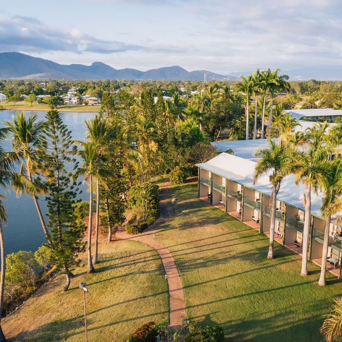 Aerial view of Mercure Hotel Townsville surrounded by palm trees, lush greenery and distant mountains
