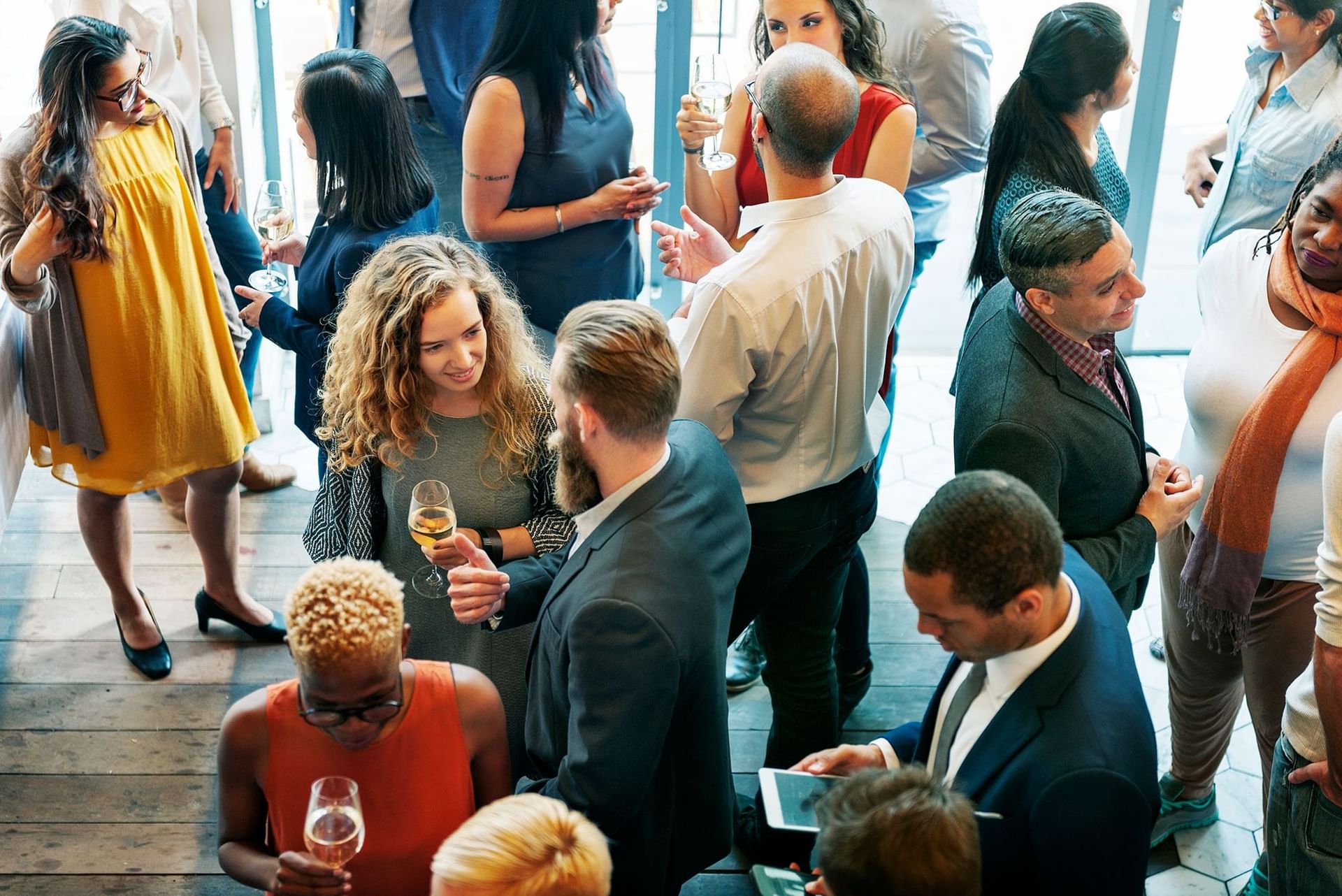A diverse group of people socializing at a professional event, holding drinks and talking to each other at High Peaks Resort
