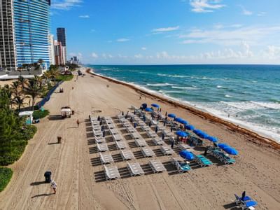 Sun beds with umbrellas by the beach near Marenas Resort Miami