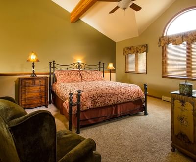 A comfortable bedroom with a queen bed, vaulted ceilings, and a large window with a view at The Stanley Hotel