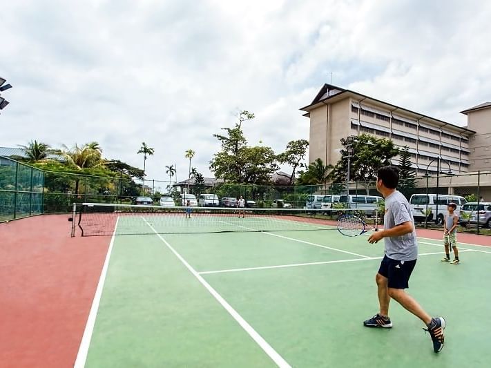 A family playing tennis on a court at Palau Royal Resort