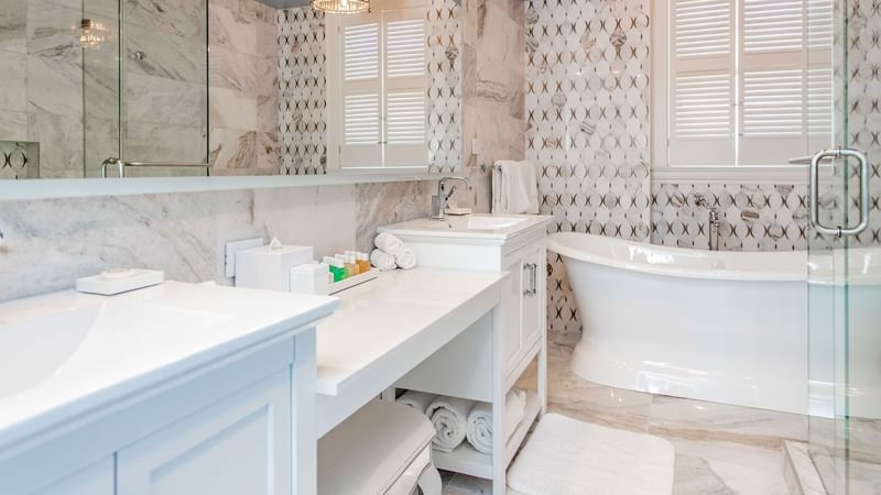 Bathroom featuring marble walls, a tub, double sinks, and toiletries in Presidential Suite at Warwick Melrose Dallas