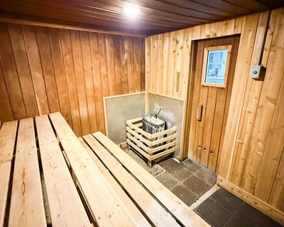 Wooden benches by a heating unit under a warm ceiling light at Rodd Charlottetown Hotel, an apartment hotel in PEI