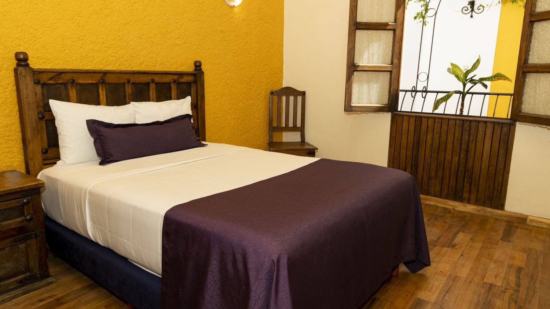 King bed, comfy pillows, window & wooden floor in a room at Gamma Puebla Senorial Centro