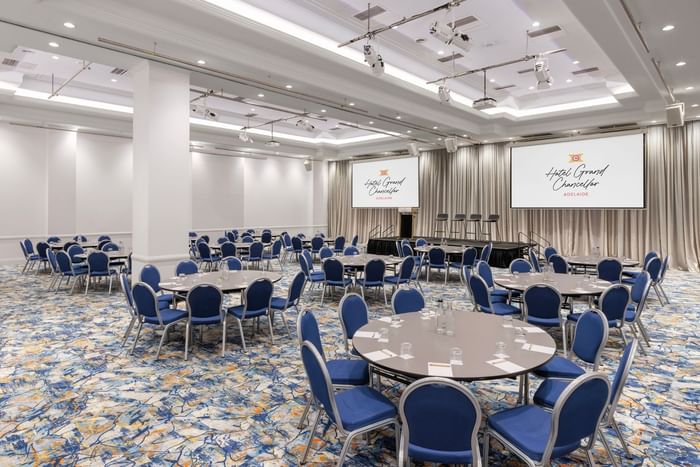 Large conference room with round tables and blue chairs at Hotel Grand Chancellor Adelaide