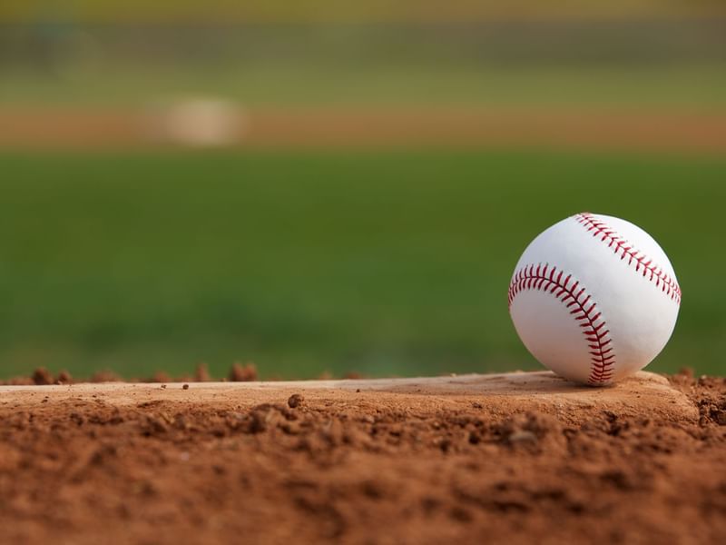 A close-up view of a baseball resting on the edge of a baseball diamond near Fiesta Inn