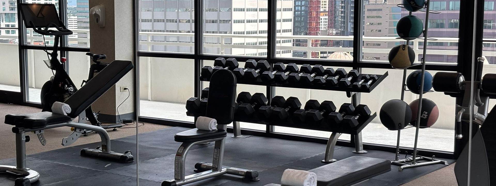 Gym with dumbbells and a weight bench by a window with city views at Warwick Denver