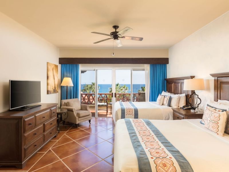 Room with two beds, traditional decor, and balcony with sea view.