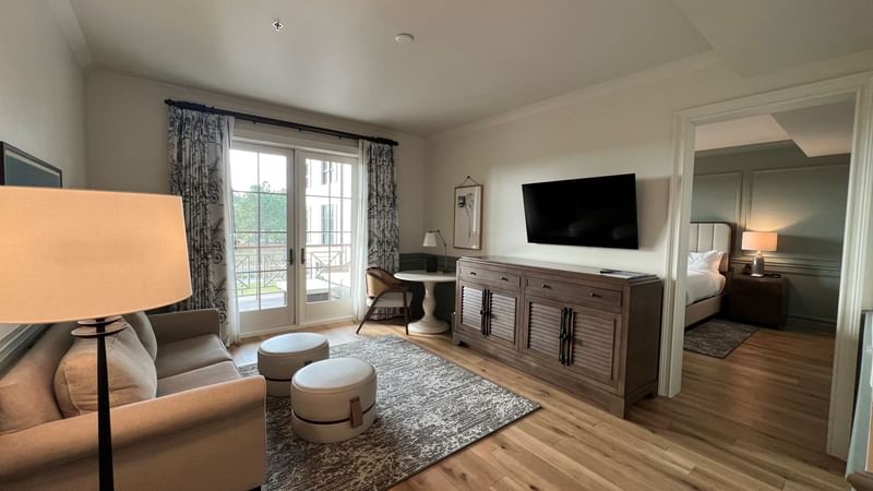 Living area with TV and ottomans by arranged seating in Pine Suite at Camp Creek Inn