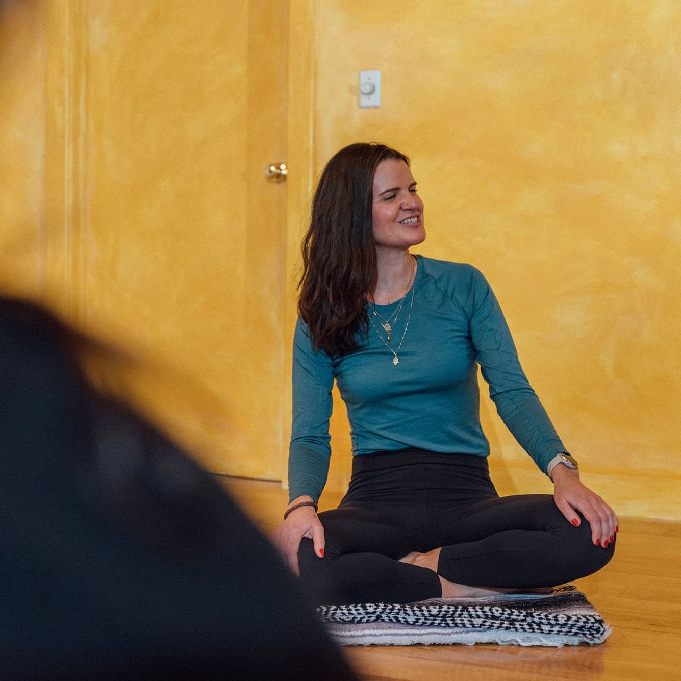 Smiling woman in lotus position on the floor.