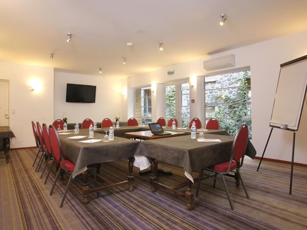 A hall arranged for a meeting with black tables and red chairs