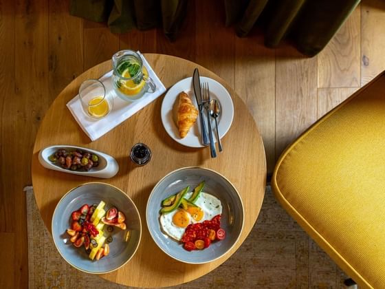 Breakfast spread with croissants, fresh fruit, sunny-side-up eggs, olives, and refreshing drinks at Ana Hotels Sport Poiana Brașov