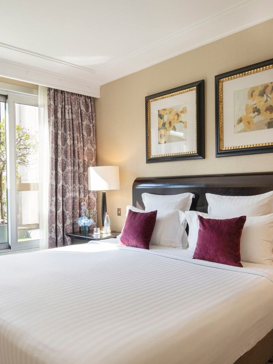 Élégante suite exécutive avec terrasse, dotée d'un lit king size, d'oreillers moelleux et d'une vue imprenable depuis la fenêtre, au Warwick Champs-Élysées Paris.