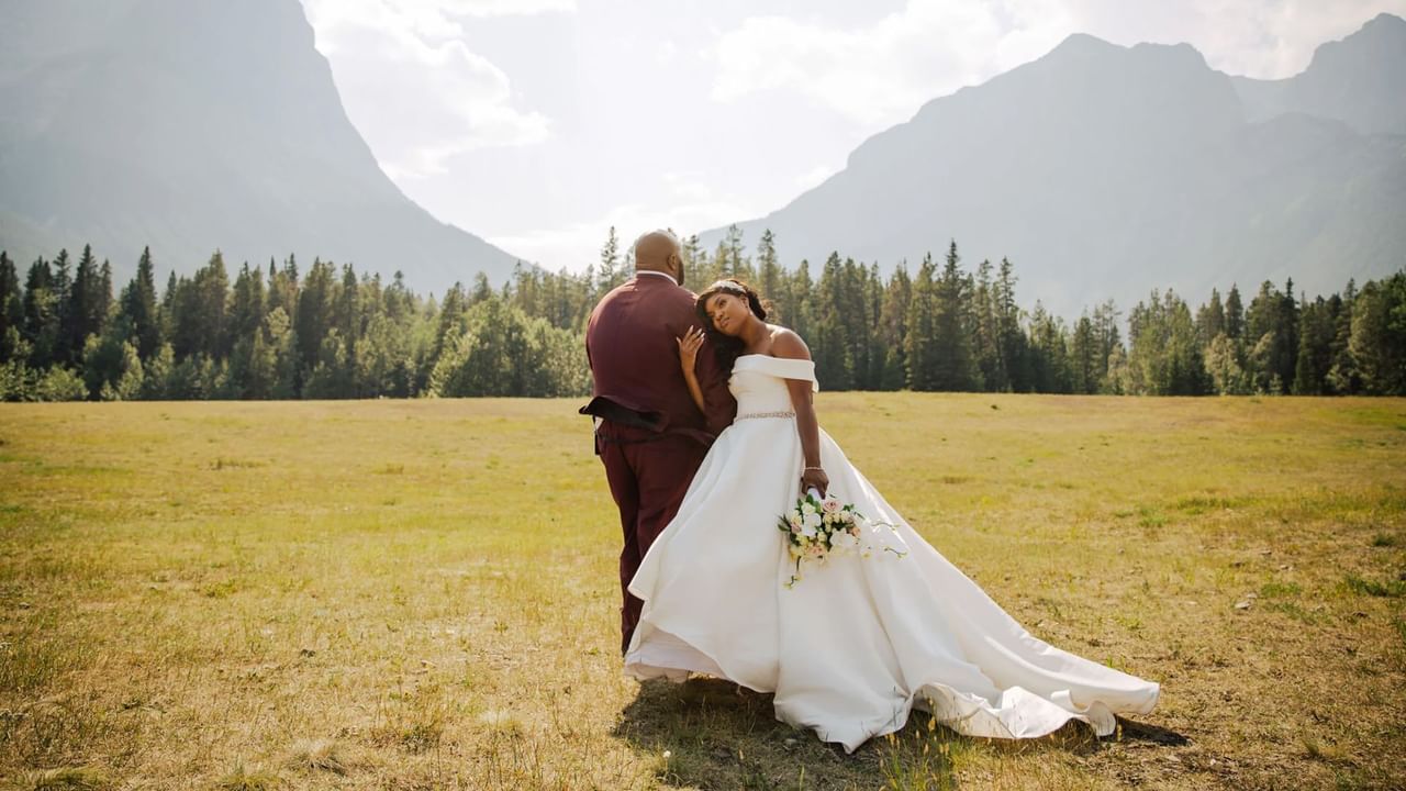 A married couple poses in front of the mountains at a mountain wedding venue in Canmore.