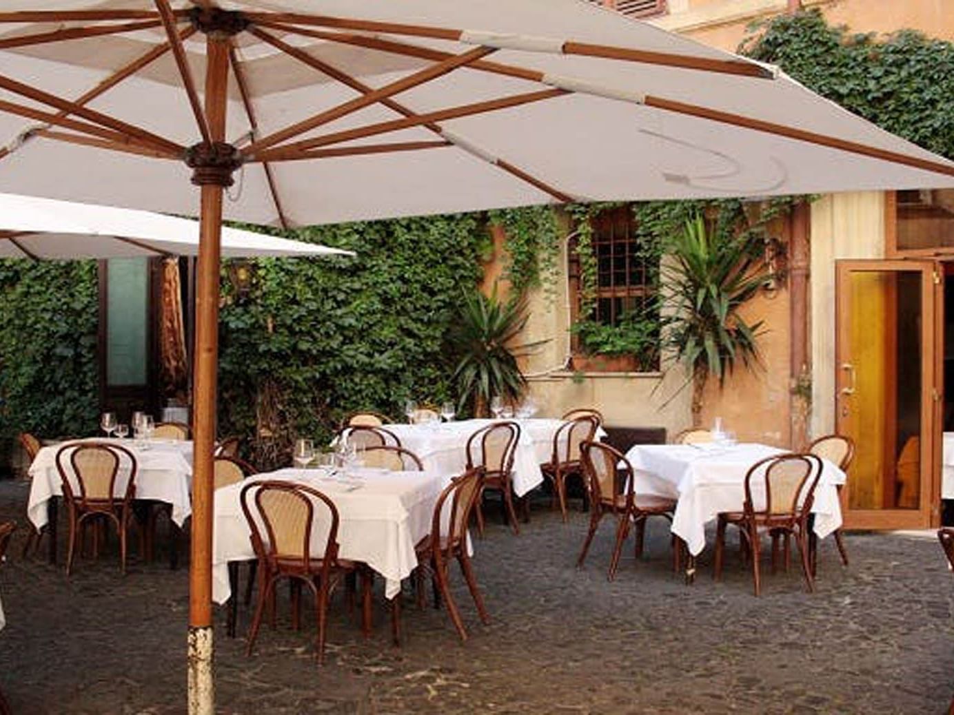 Piperno Restaurant outdoor dining with wooden chairs, large umbrellas, and lush greenery near The Guardian Hotel