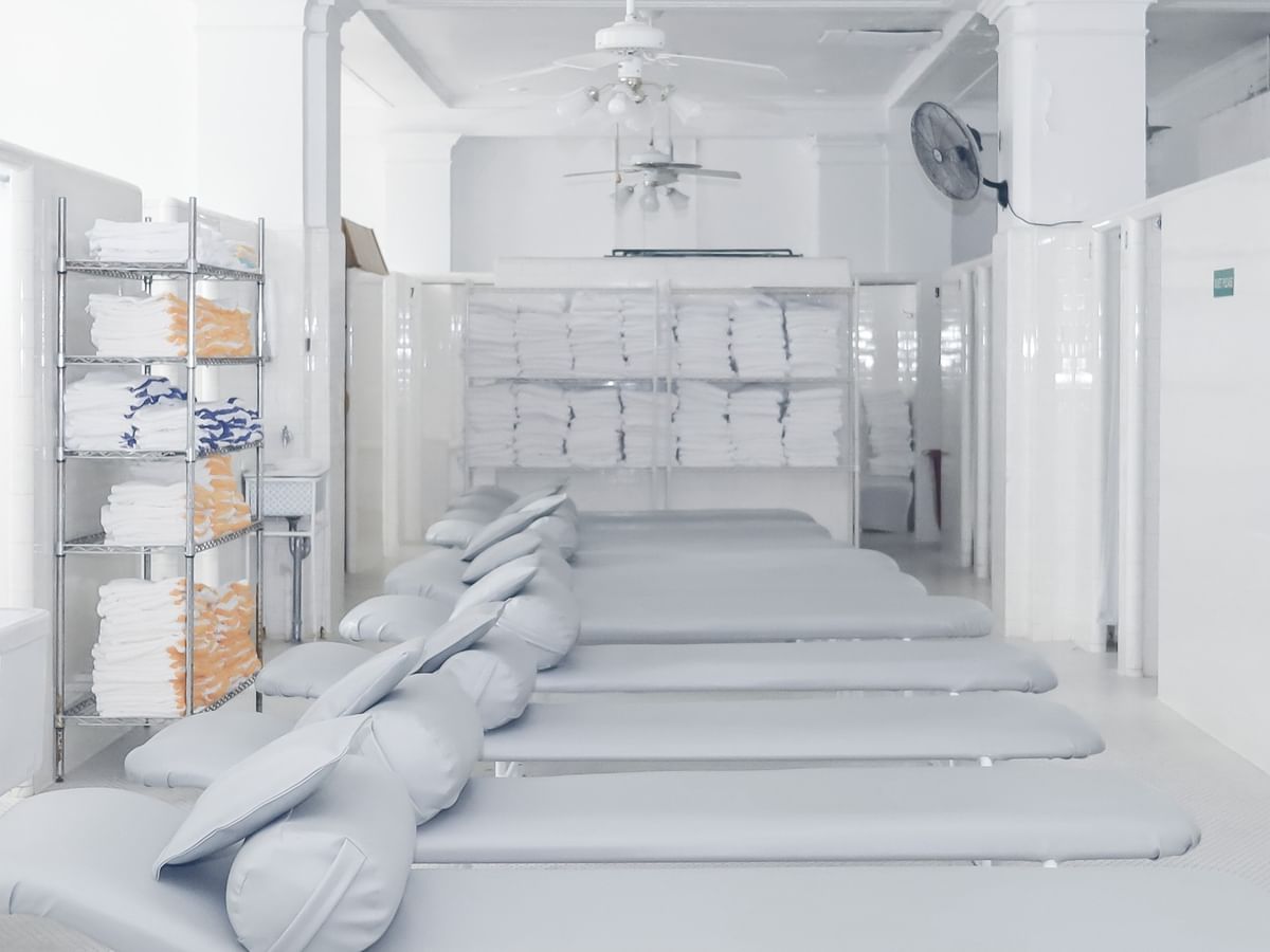White padded loungers by a metal towel rack under a high white ceiling in spa at Arlington Resort Hotel & Spa