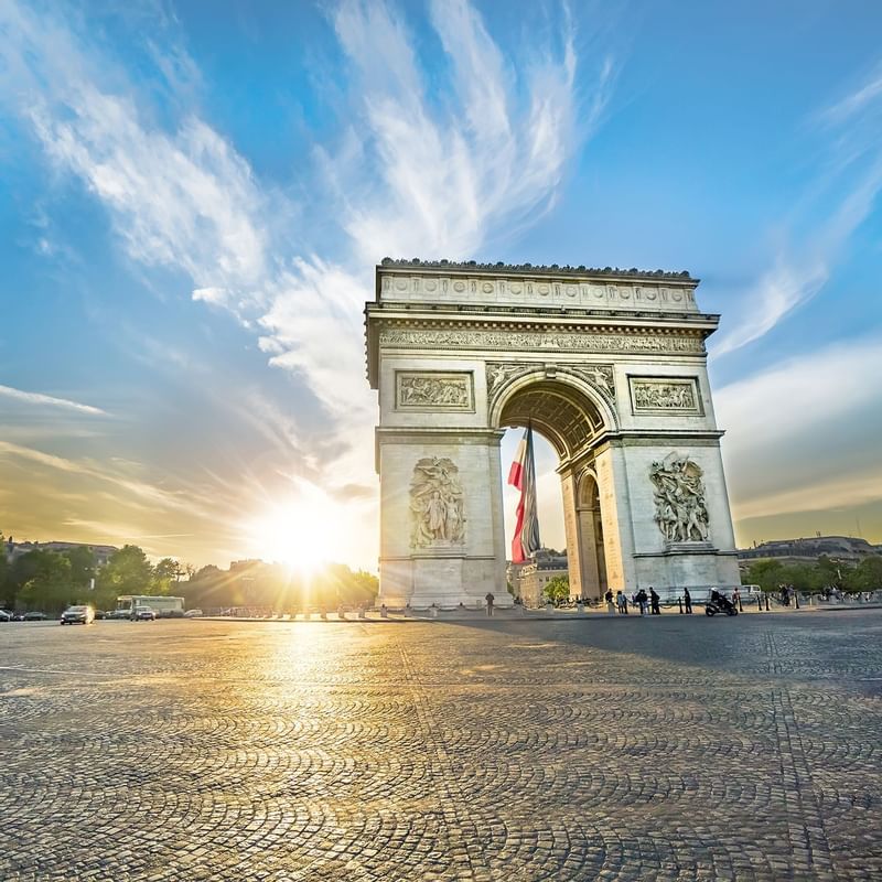 The Arc de Triomphe stands majestically as the sun sets behind it, featuring locations near Warwick Hotels and Resorts