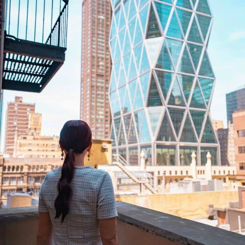 A woman looks out over a cityscape from a balcony.