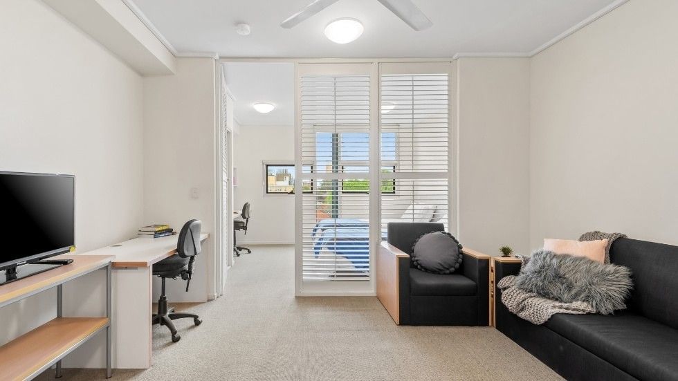 Modern living room with furniture, desk, and TV, highlighting the benefits of fully furnished apartments for students.