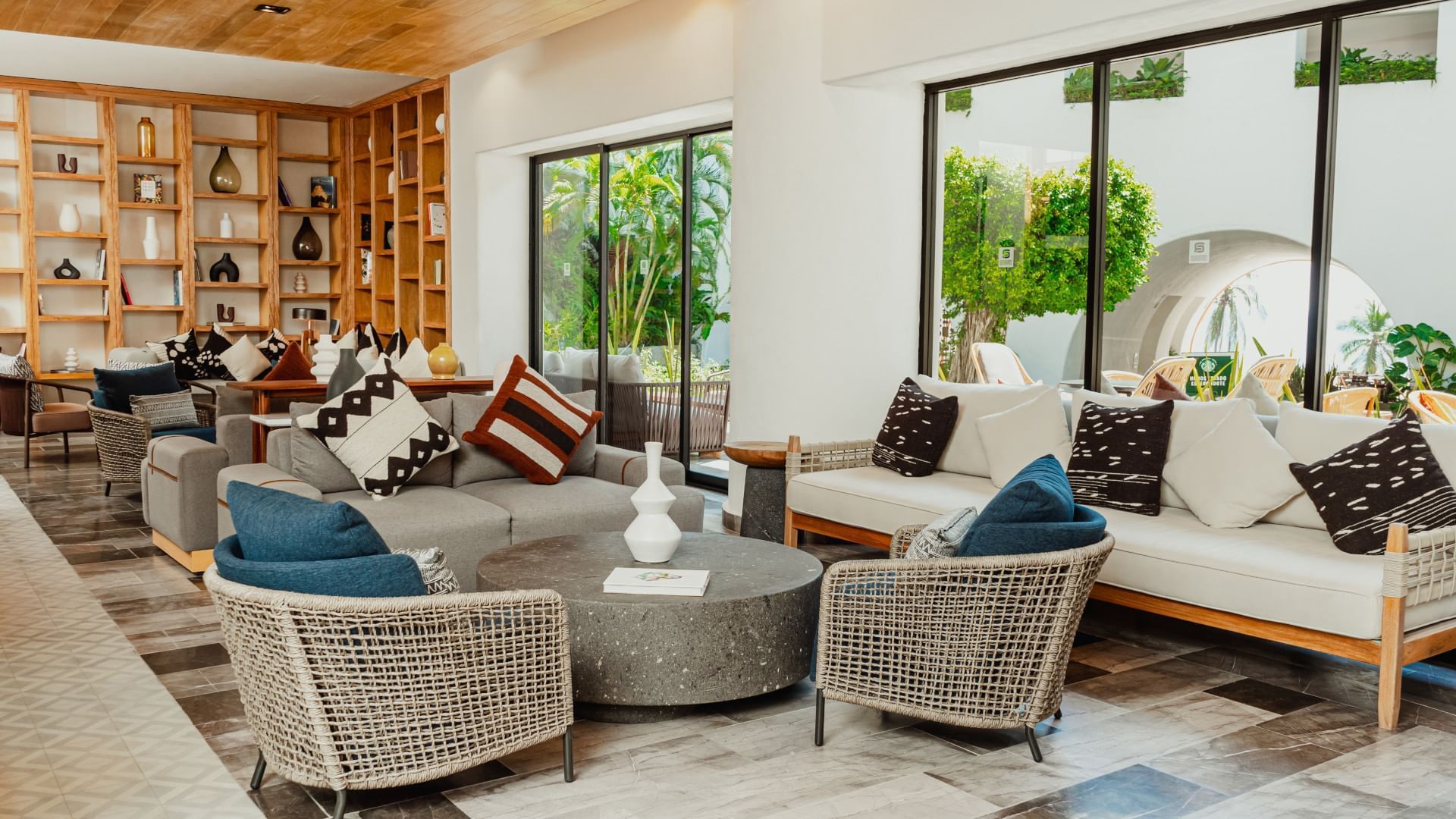Modern lounge with sofas, wooden shelves, & a distant ocean view in Library Café & Deli at Camino Real Zaashila Huatulco