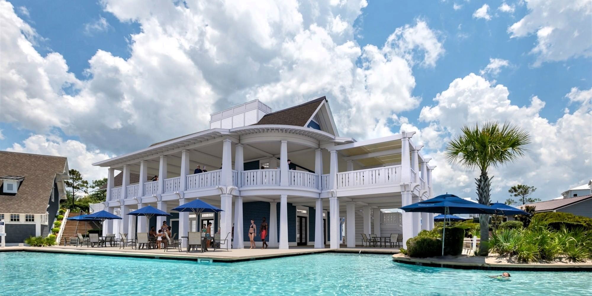 White building with balconies and blue umbrellas by pool at 30°86° in Inlet Beach.
