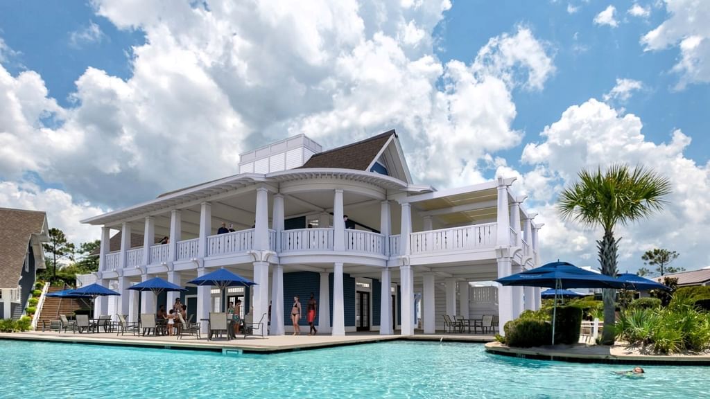 White building with balconies and blue umbrellas by pool at 30°86° in Inlet Beach.