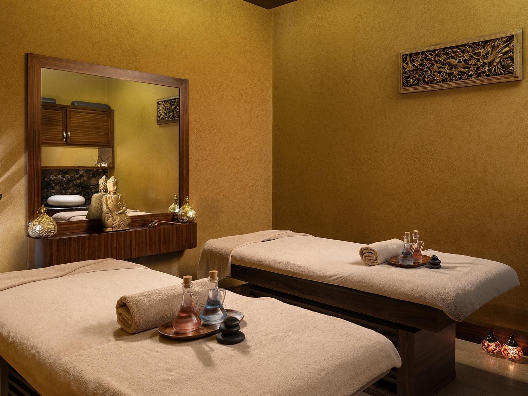 Two massage tables with towels, bottles, and decorative items in the spa massage room at Titanic City Taksim