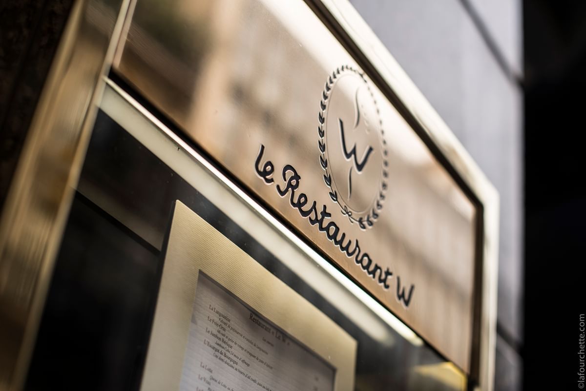 A close-up of the sign for le Restaurant W, with a logo and visible menu in Restaurant-Le W